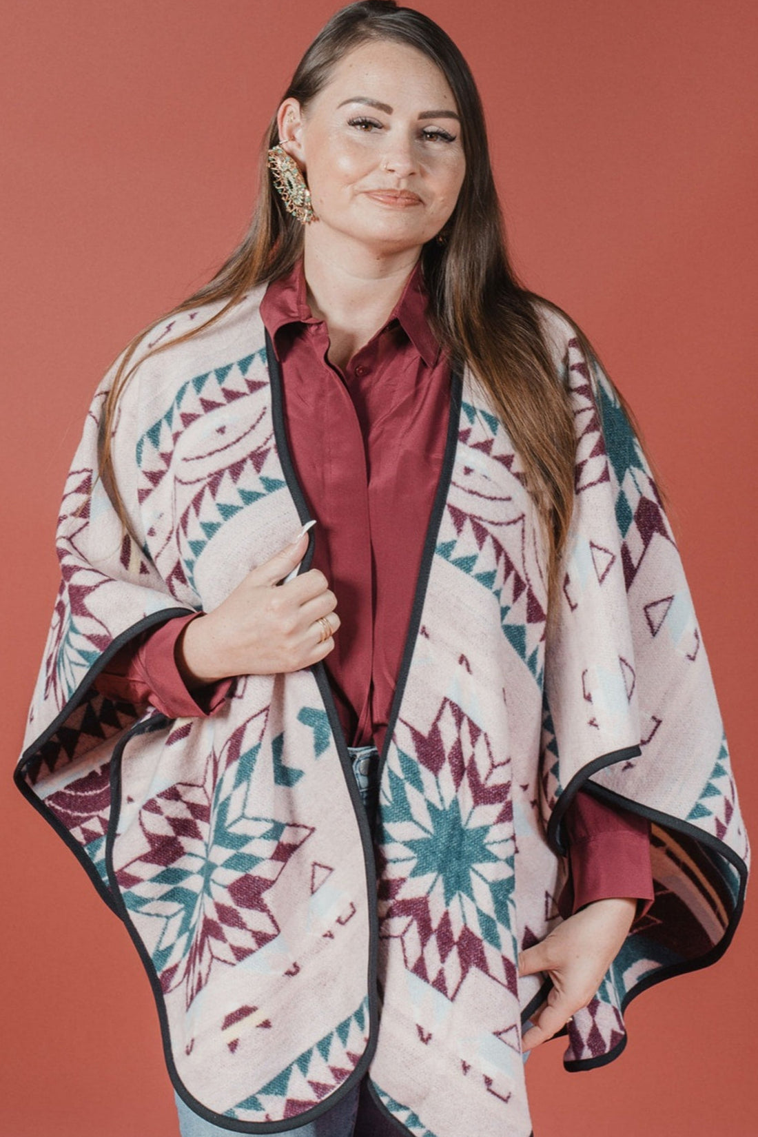 Woman wearing a patterned poncho against a red background